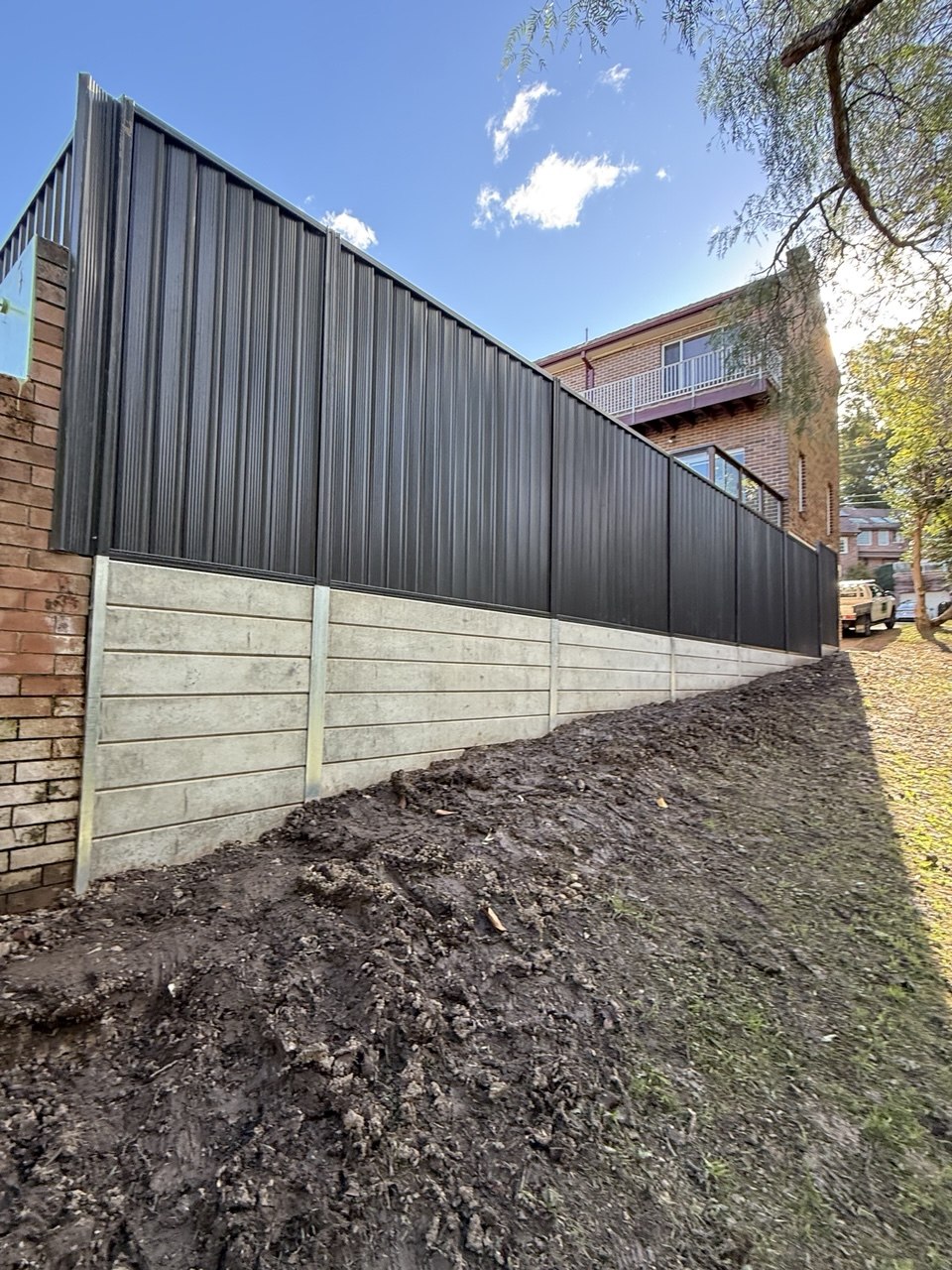 Concrete sleeper retaining wall Sydney with Colorbond fence