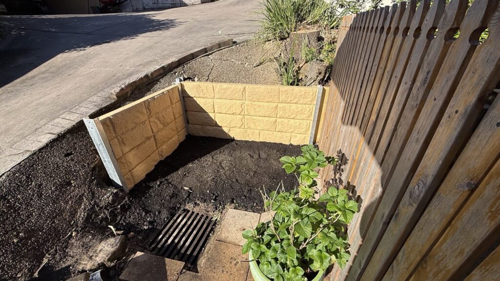 Split-face concrete block garden box corner return with fresh soil and drainage grate, Eastwood Sydney