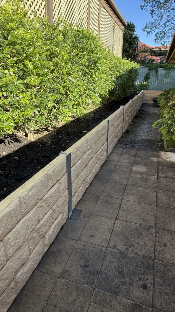 Split-face concrete block garden box beside a paved walkway in Eastwood, Sydney, planted with shrubs