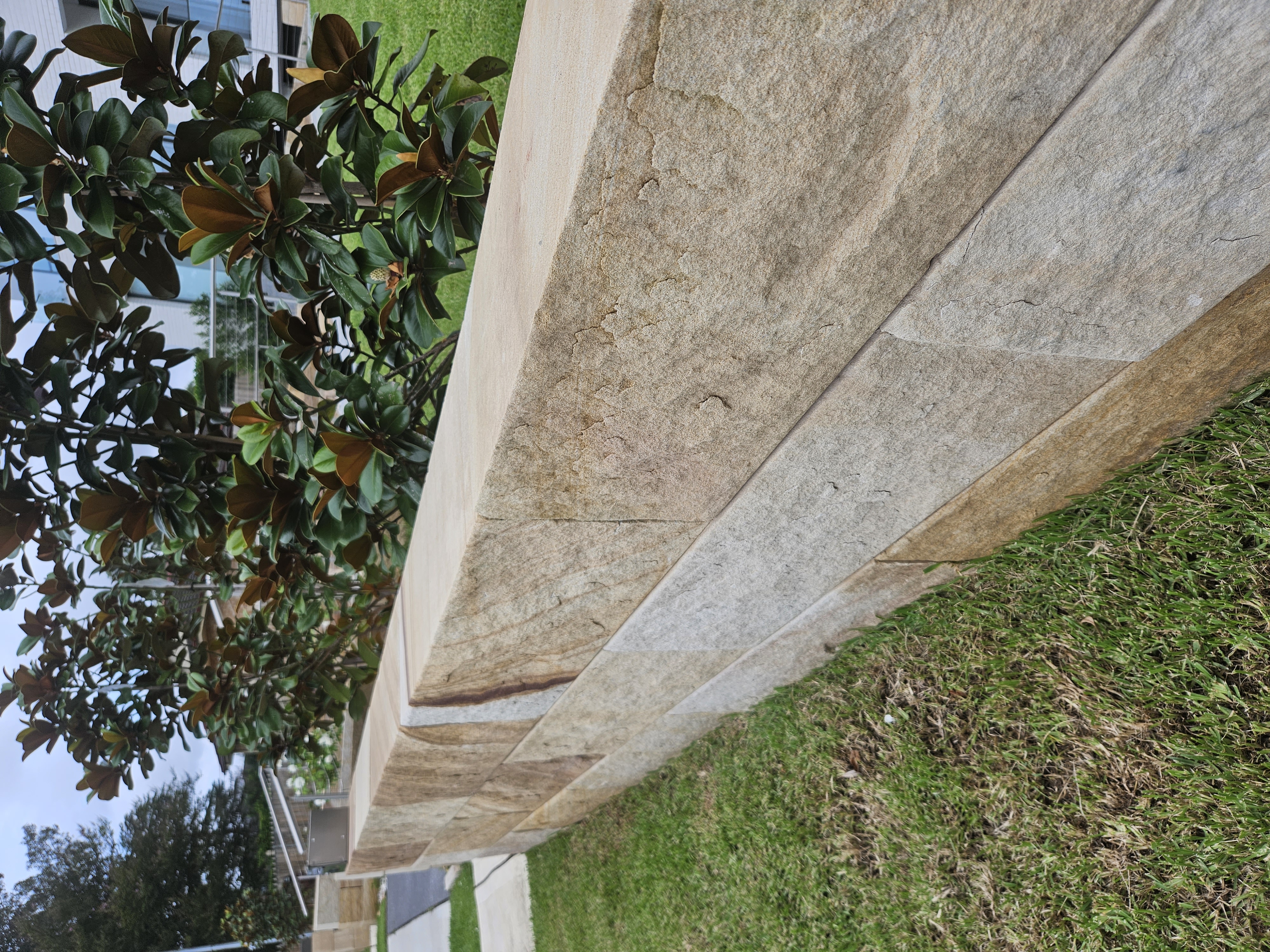 Sandstone block wall showing natural bedding lines and colour variation between blocks