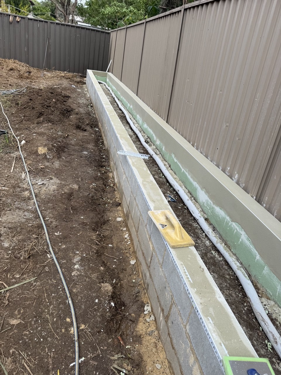 Polyurethane waterproofing membrane applied to the back of a reinforced block garden box with drainage line installed, Eastwood Sydney