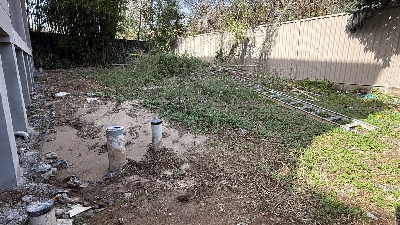 Bare backyard with weeds and exposed stormwater pipes before landscaping, Eastwood Sydney