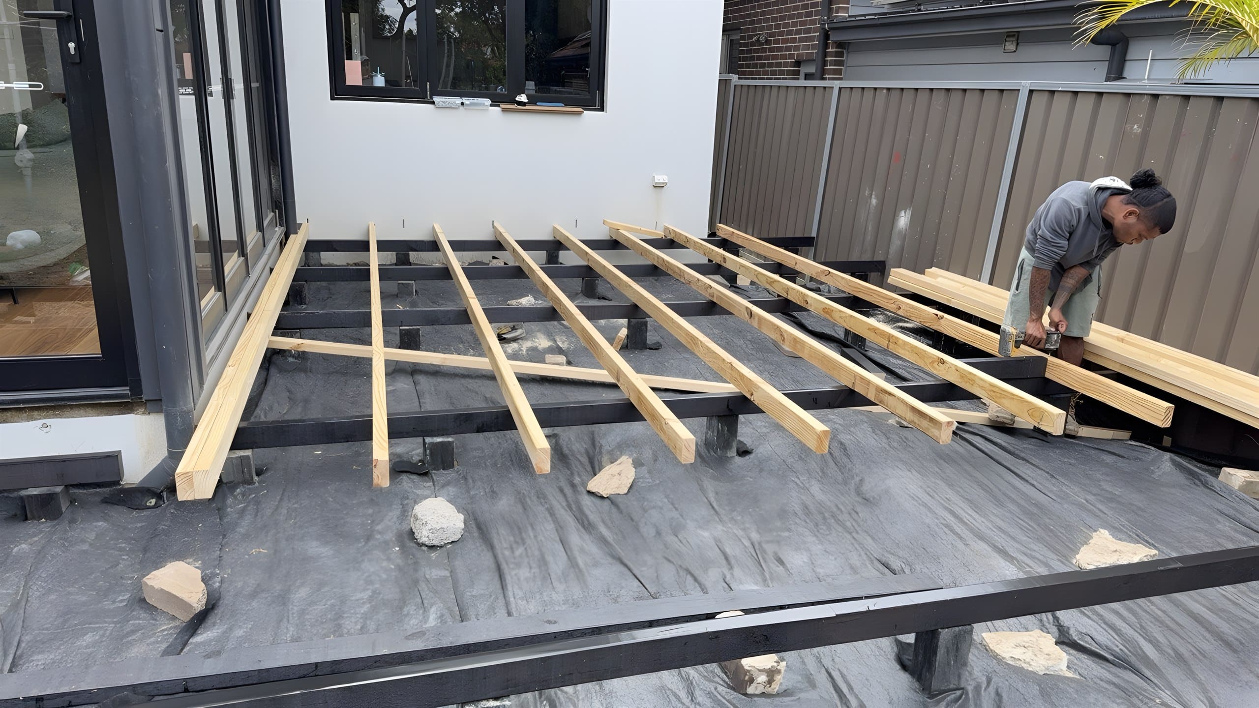 Deck bearers and joists being installed beside bi-fold doors in Five Dock