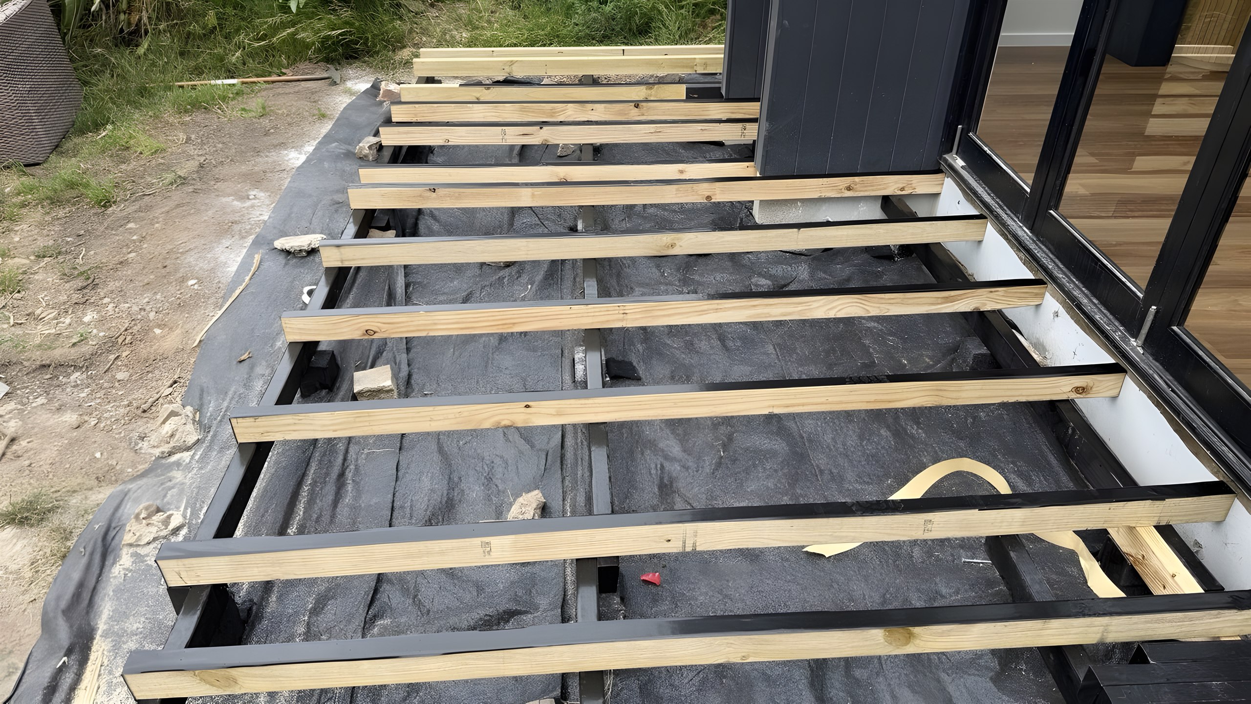 New deck joists over weed mat beside bi-fold doors in Five Dock