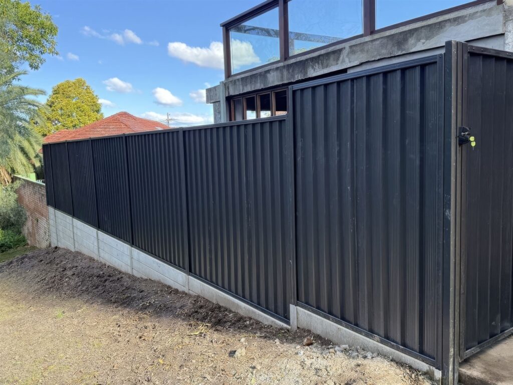 Concrete sleeper wall with black Colorbond fence